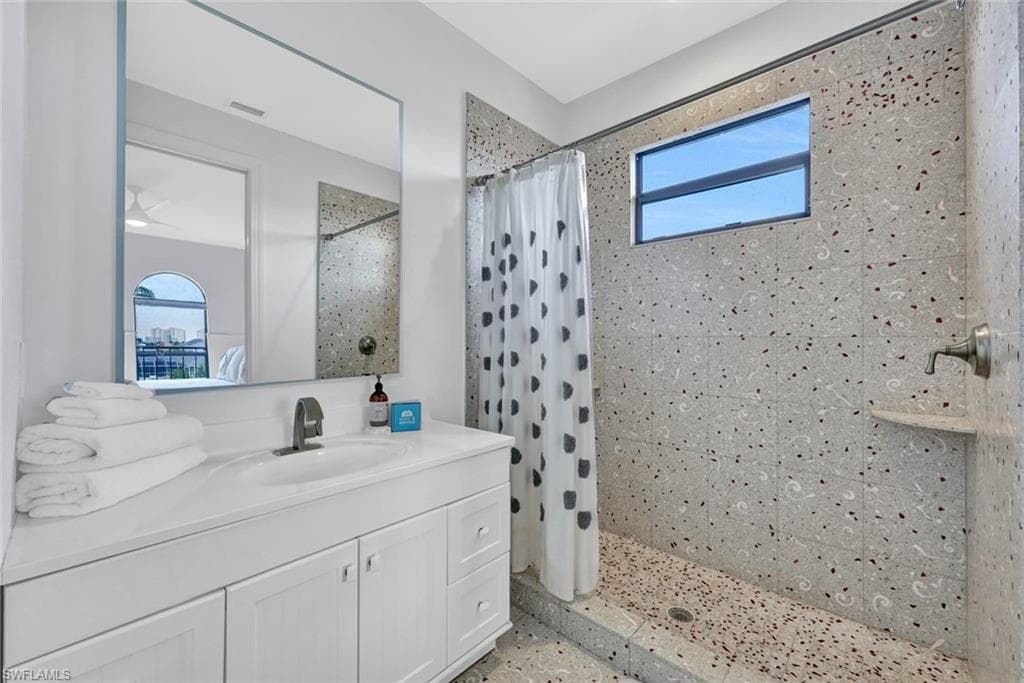 Bathroom featuring vanity, tiled shower, and plenty of natural light