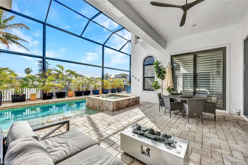 View of patio with a sunroom, a lanai, outdoor dining space, a ceiling fan, and a pool with connected hot tub