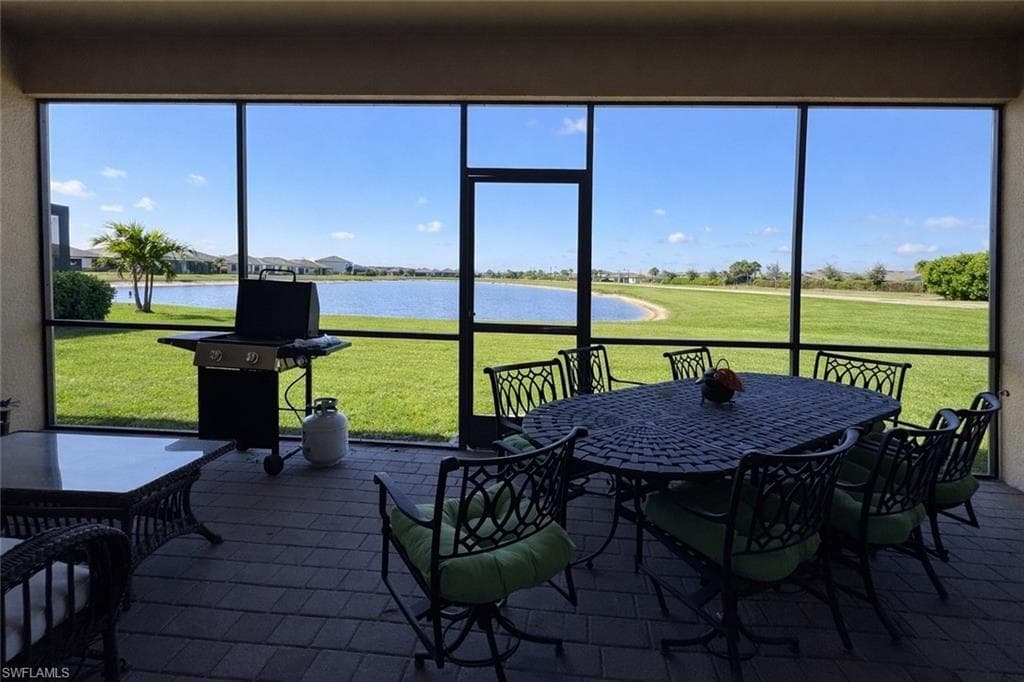 Sunroom with a water view, outdoor dining area, and a residential view