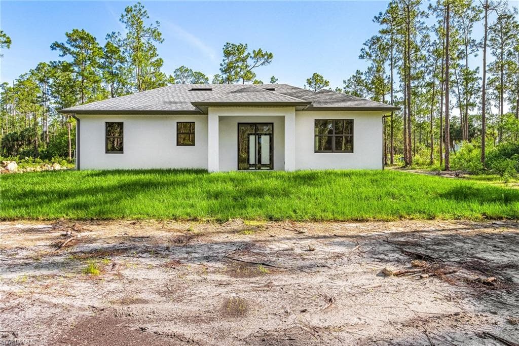 Back of property featuring stucco siding and roof with shingles