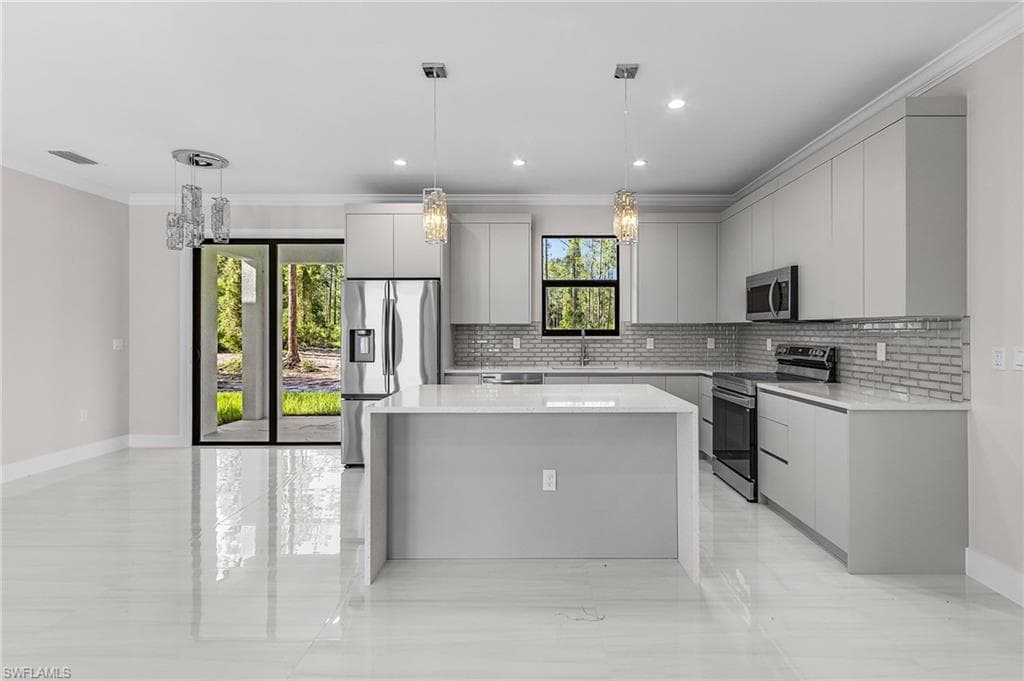Kitchen with modern cabinets, a kitchen island, stainless steel appliances, hanging light fixtures, and ornamental molding