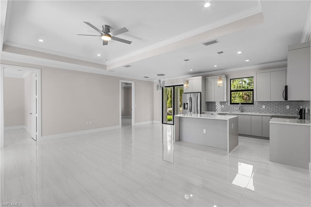 Kitchen featuring gray cabinetry, open floor plan, tasteful backsplash, hanging light fixtures, and a center island