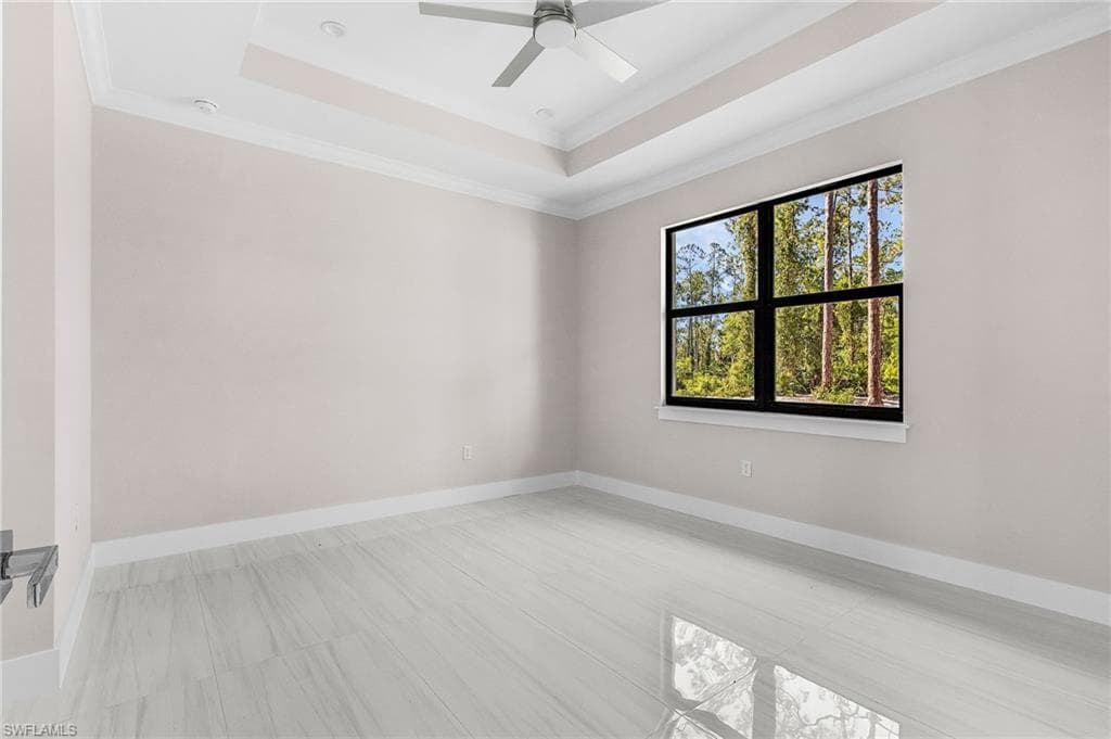 Empty room featuring crown molding, a ceiling fan, and a raised ceiling