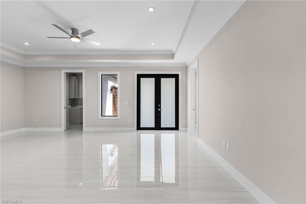 Unfurnished room with french doors, a raised ceiling, ornamental molding, and ceiling fan