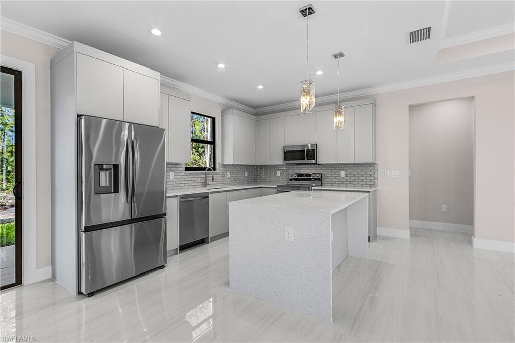 Kitchen with stainless steel appliances, ornamental molding, a center island, pendant lighting, and modern cabinets