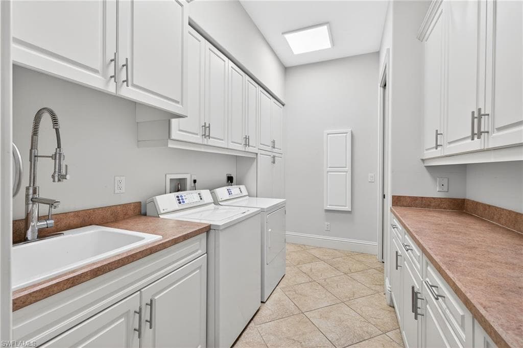 Laundry area with cabinet space, washer and dryer, and light tile patterned flooring