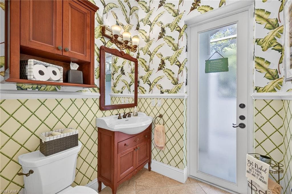 Half bathroom featuring wallpapered walls, vanity, and light tile patterned floors
