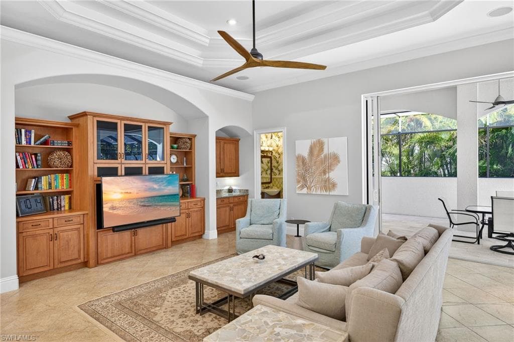 Living area with ceiling fan, crown molding, arched walkways, recessed lighting, and a tray ceiling