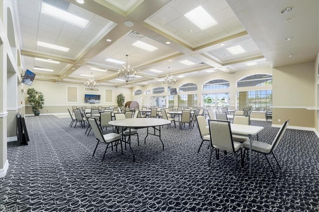 Dining room featuring dark colored carpet, coffered ceiling, and a chandelier
