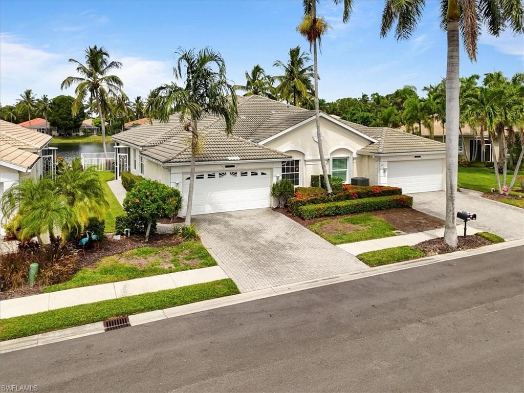 Ranch-style home with a tile roof, driveway, stucco siding, and a garage