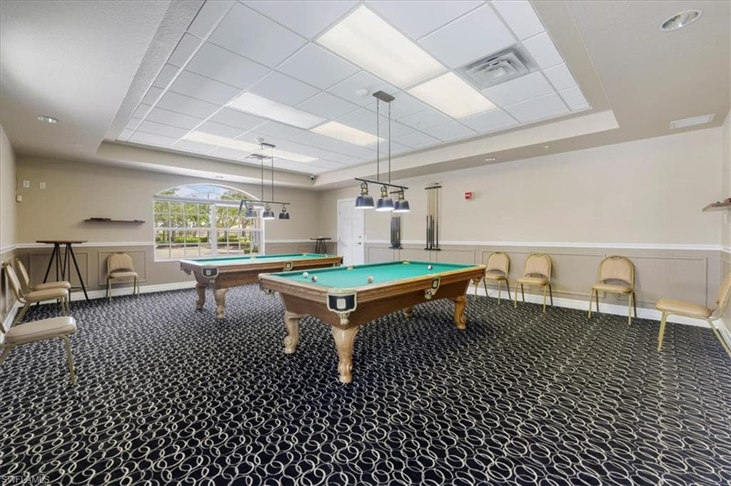 Rec room with a raised ceiling, billiards, wainscoting, and a decorative wall