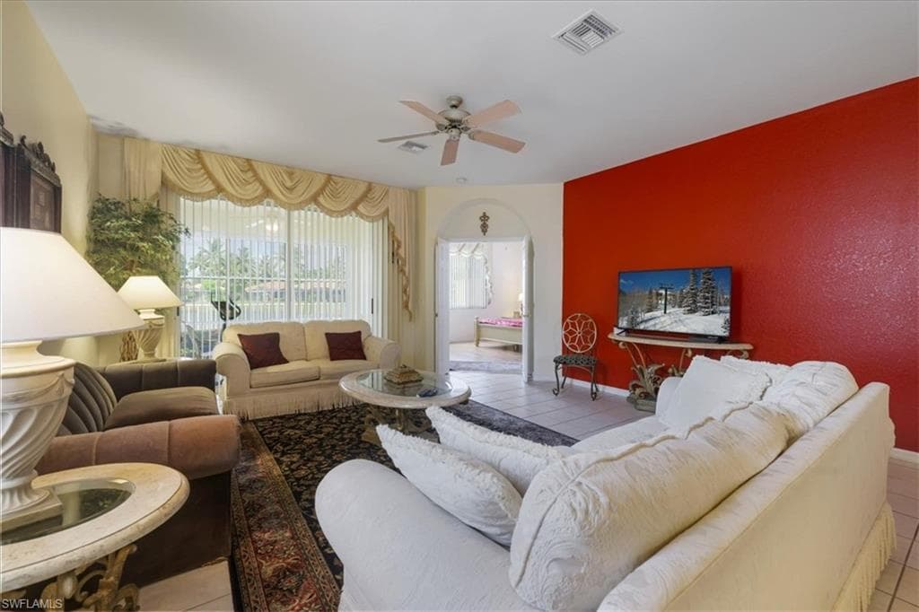Living area featuring ceiling fan, arched walkways, and light tile patterned floors