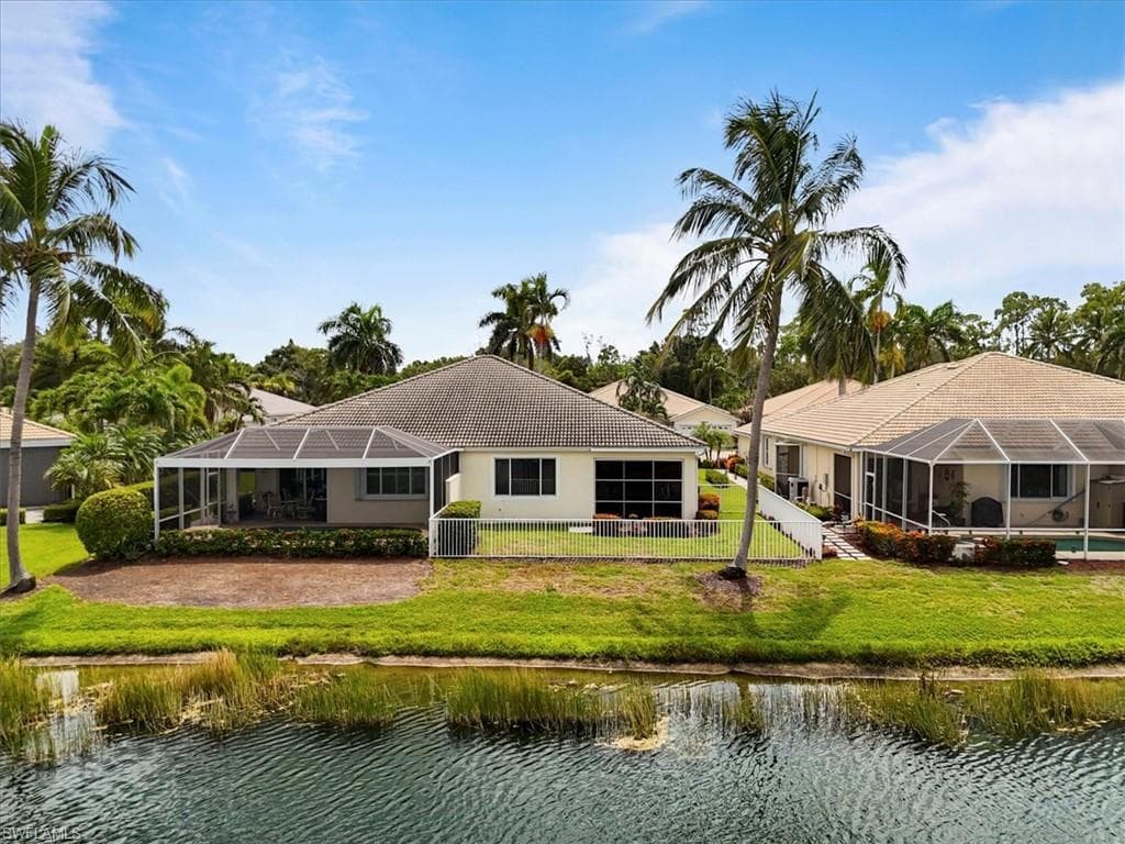 Rear view of property with a sunroom, a water view, a fenced backyard, and a lanai