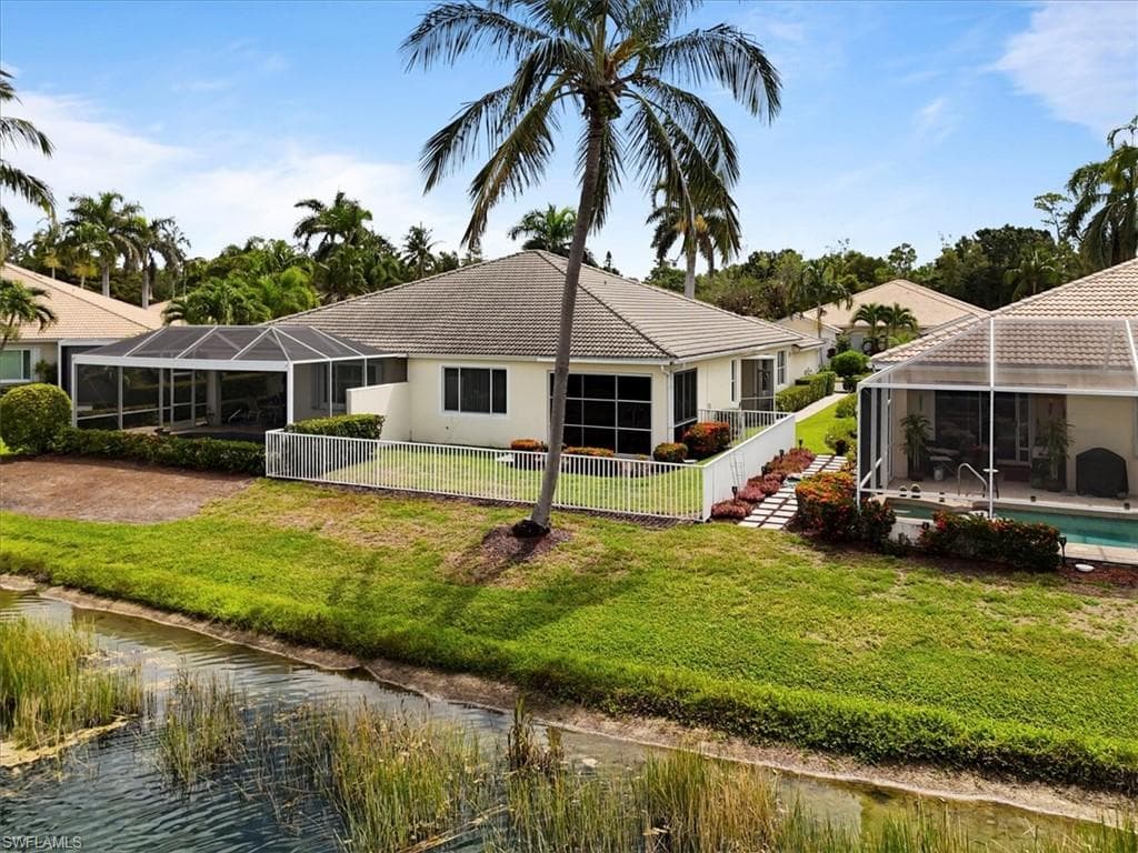 Rear view of house featuring a lanai, a sunroom, a fenced backyard, and a water view
