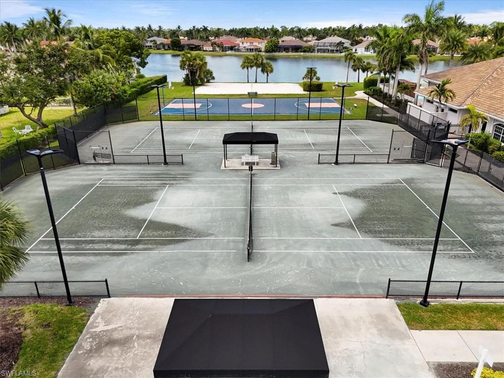 View of tennis court featuring a water view and a residential view