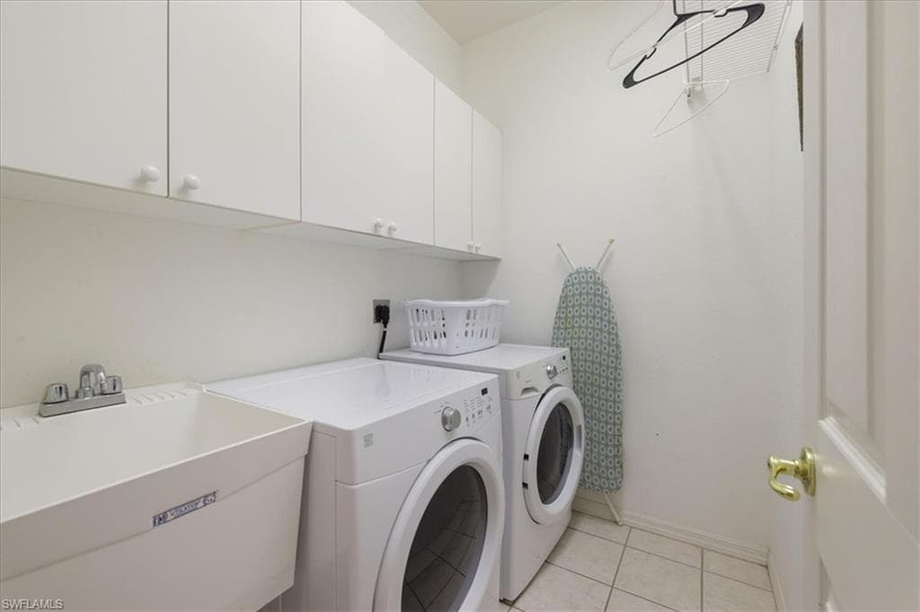 Laundry area featuring cabinet space, washer and clothes dryer, and light tile patterned floors
