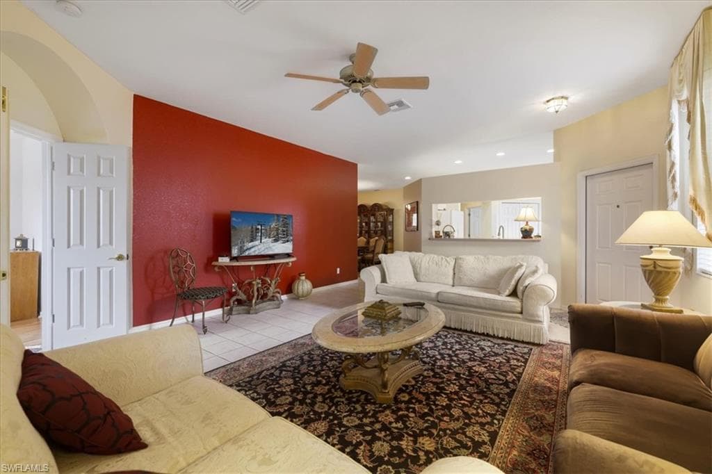 Tiled living room with a ceiling fan and arched walkways