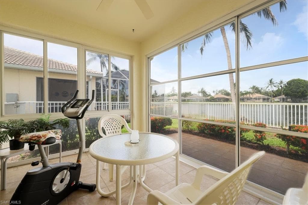 Sunroom / solarium featuring a residential view, a water view, and tile patterned flooring