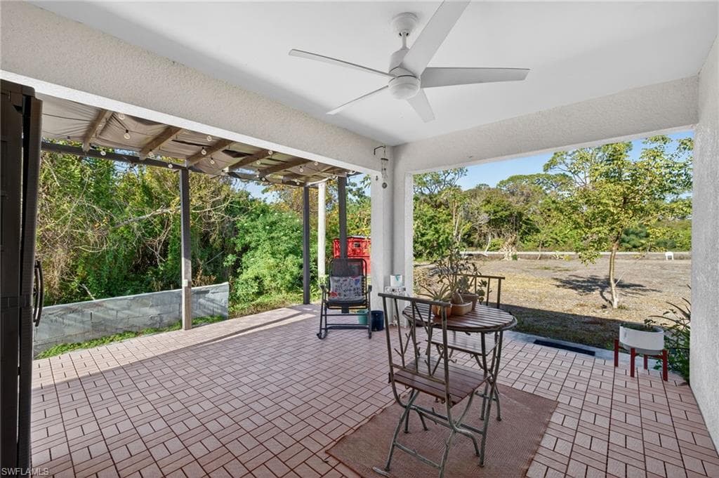 View of patio with a ceiling fan and view of scattered trees