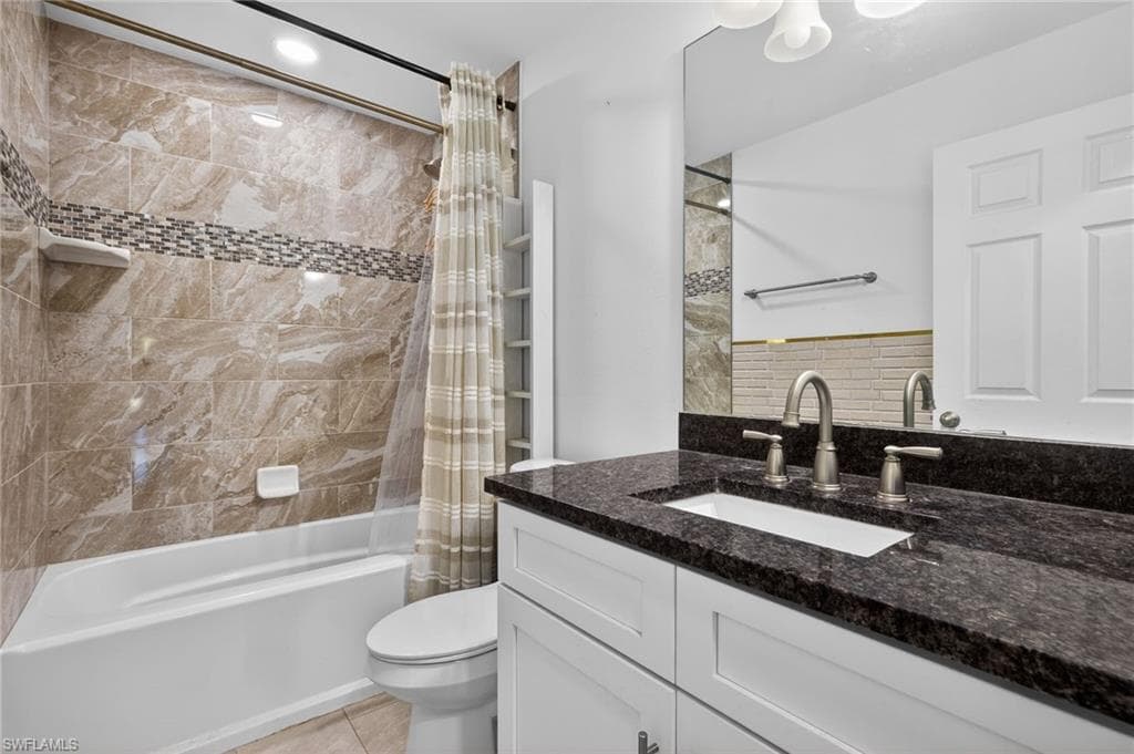 Bathroom featuring shower / bath combination with curtain, vanity, and light tile patterned floors