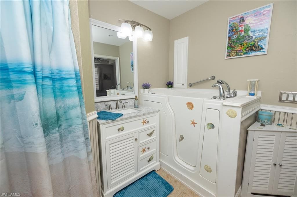 Full bath featuring vanity, a garden tub, and light tile patterned floors