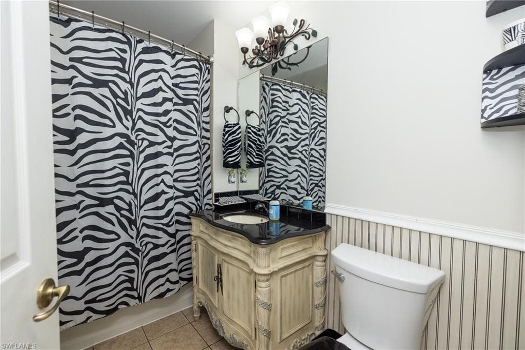 Bathroom with wainscoting, vanity, curtained shower, and light tile patterned floors
