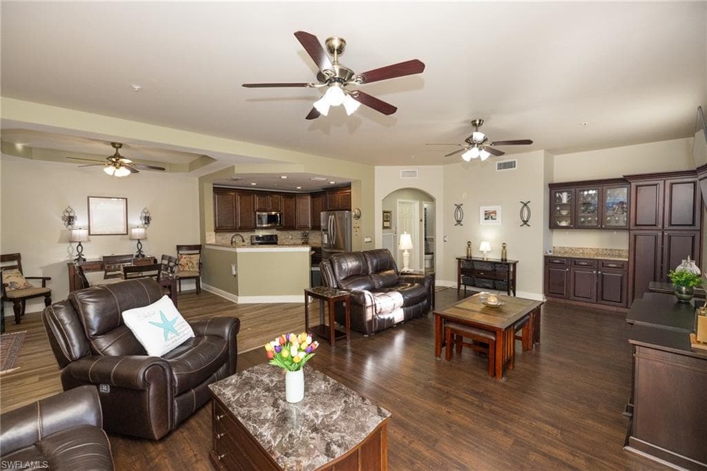 Living area with a ceiling fan, arched walkways, dark wood-style floors, and recessed lighting
