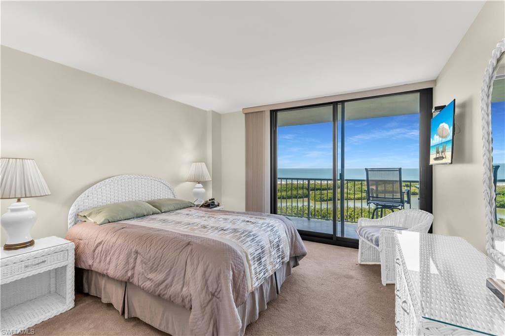 Bedroom with access to exterior, expansive windows, and carpet