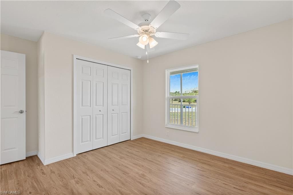 Unfurnished bedroom featuring light wood-style flooring, a closet, and ceiling fan