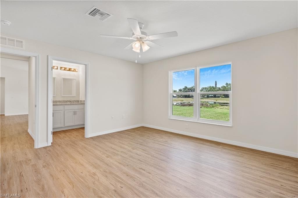 Unfurnished bedroom featuring light wood-style floors, ceiling fan, and ensuite bath