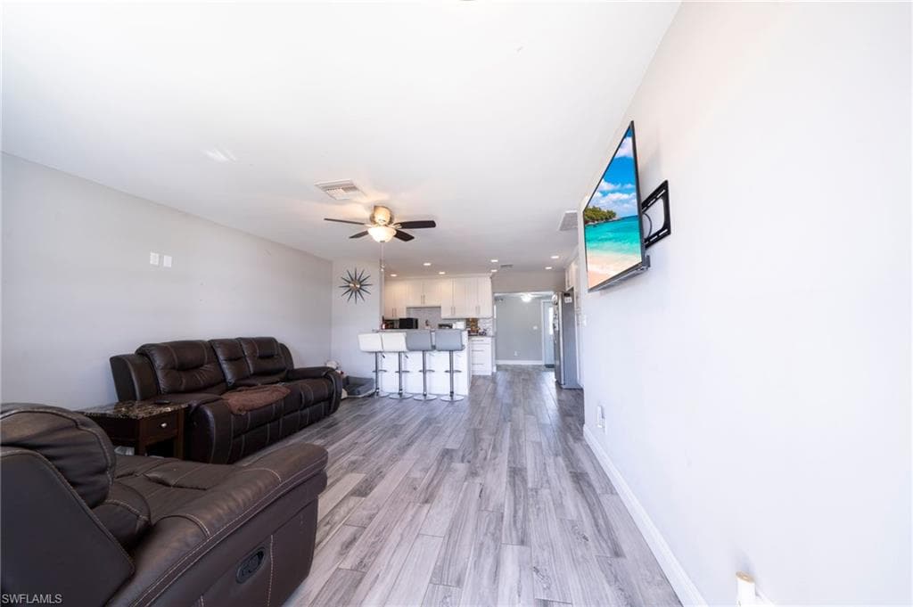 Living room with light wood-style flooring and ceiling fan