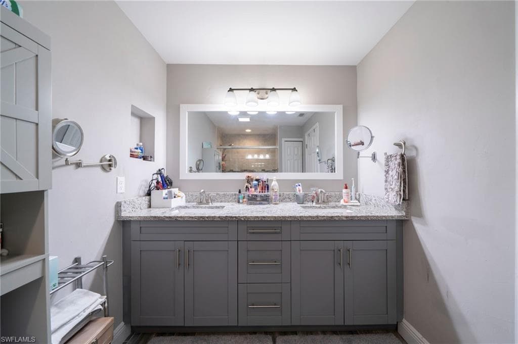 Full bath with double vanity and a tile shower