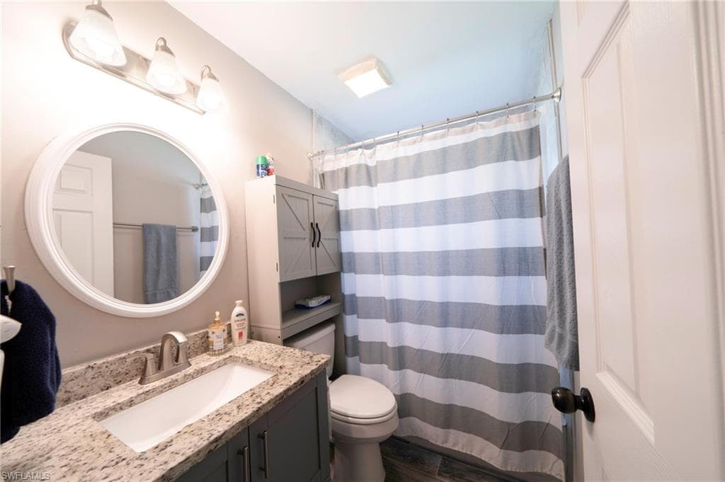 Bathroom with a shower with shower curtain, vanity, and dark wood-style flooring