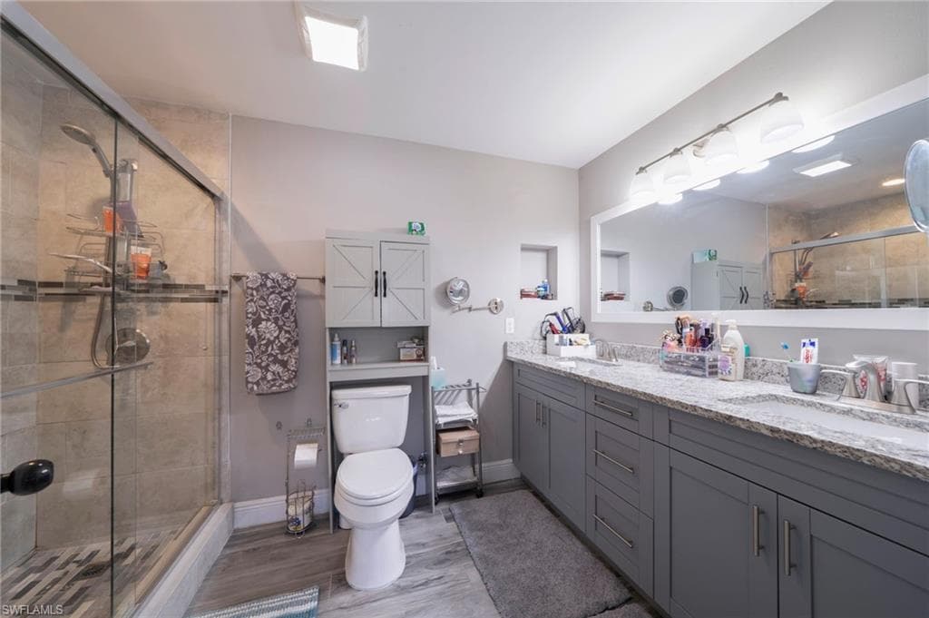 Bathroom with a shower stall, double vanity, and light wood-style floors