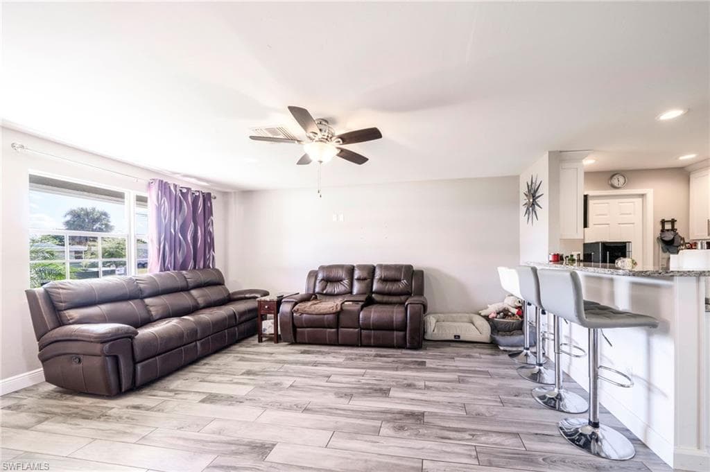 Living room with wood finish floors, ceiling fan, and recessed lighting