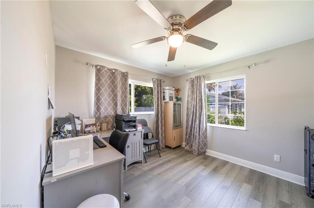 Office area with light wood-style floors and a ceiling fan