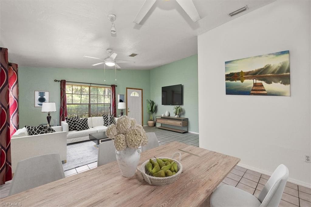 Dining room featuring light tile patterned floors, vaulted ceiling, and a ceiling fan