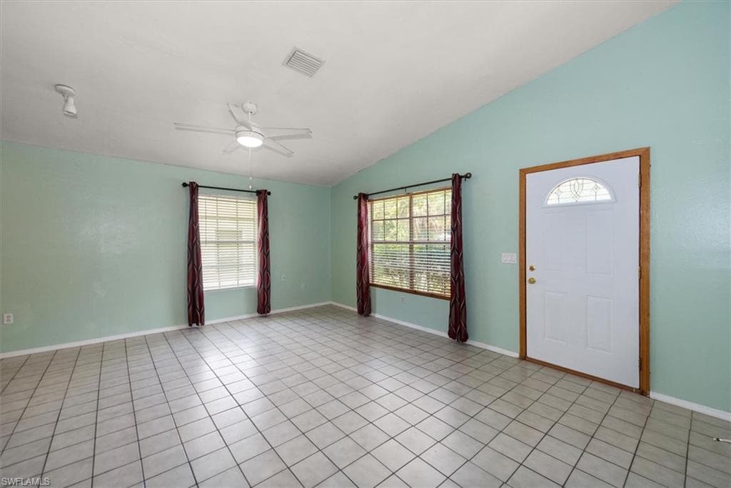 Foyer with a ceiling fan, vaulted ceiling, plenty of natural light, and light tile patterned floors