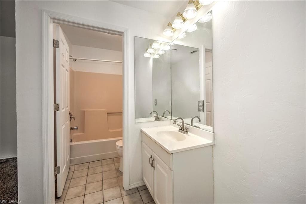 Bathroom featuring vanity, shower / tub combination, and light tile patterned floors