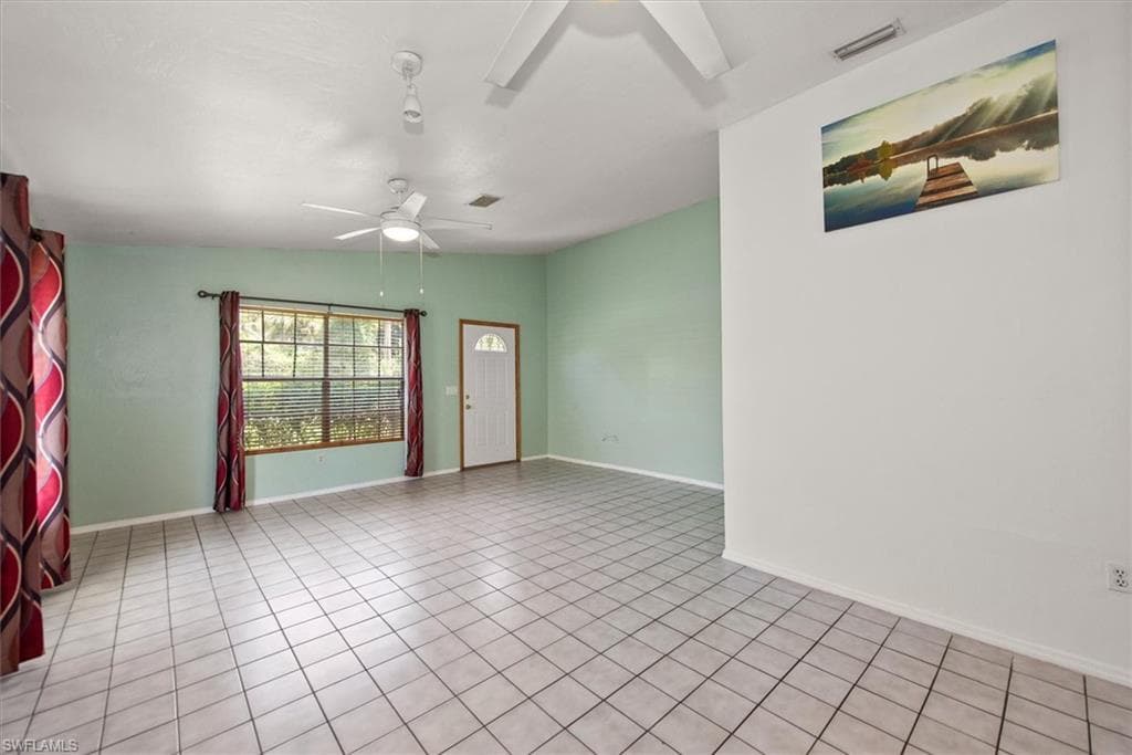 Unfurnished room with a ceiling fan, vaulted ceiling, and light tile patterned floors