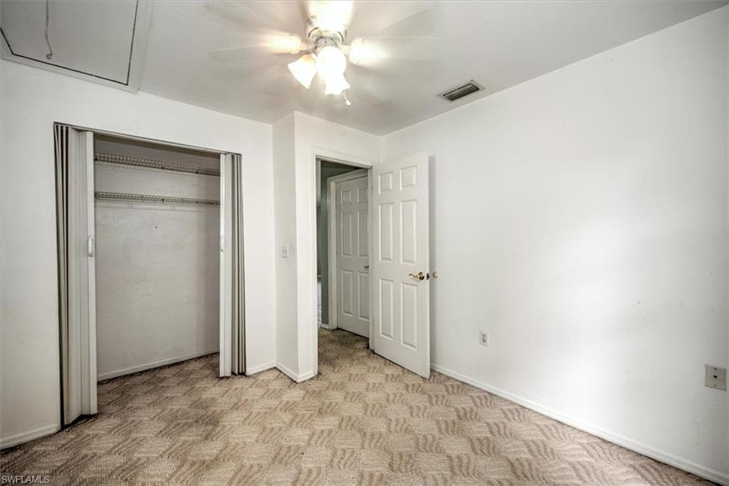 Unfurnished bedroom featuring ceiling fan, light carpet, and a closet