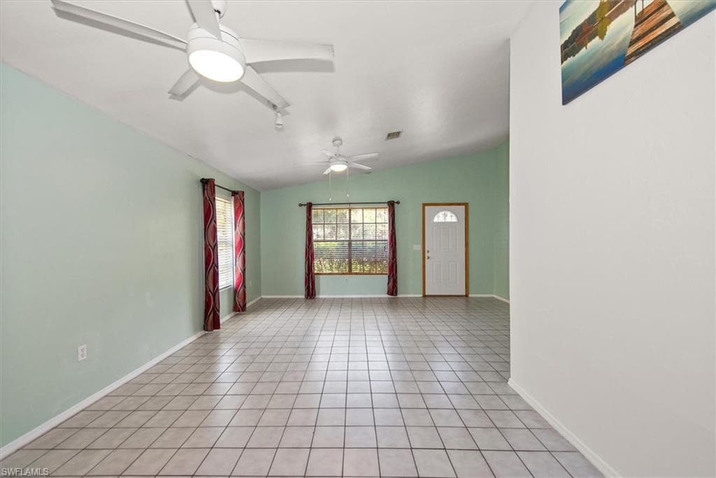 Unfurnished room with light tile patterned floors, ceiling fan, and vaulted ceiling