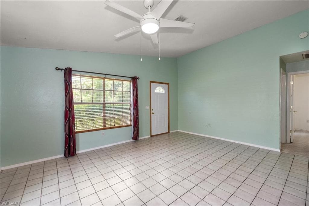 Empty room with ceiling fan and light tile patterned flooring
