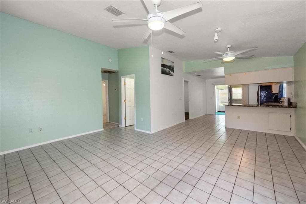Unfurnished living room featuring light tile patterned floors, a ceiling fan, and vaulted ceiling