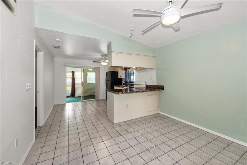 Kitchen with vaulted ceiling, light tile patterned flooring, a ceiling fan, a peninsula, and white range