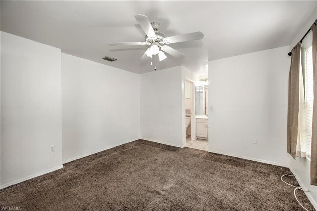 Unfurnished bedroom featuring carpet, ceiling fan, and connected bathroom