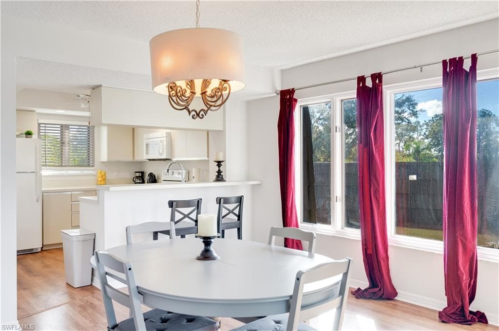 Dining space featuring light wood-style floors, plenty of natural light, a textured ceiling, and a chandelier