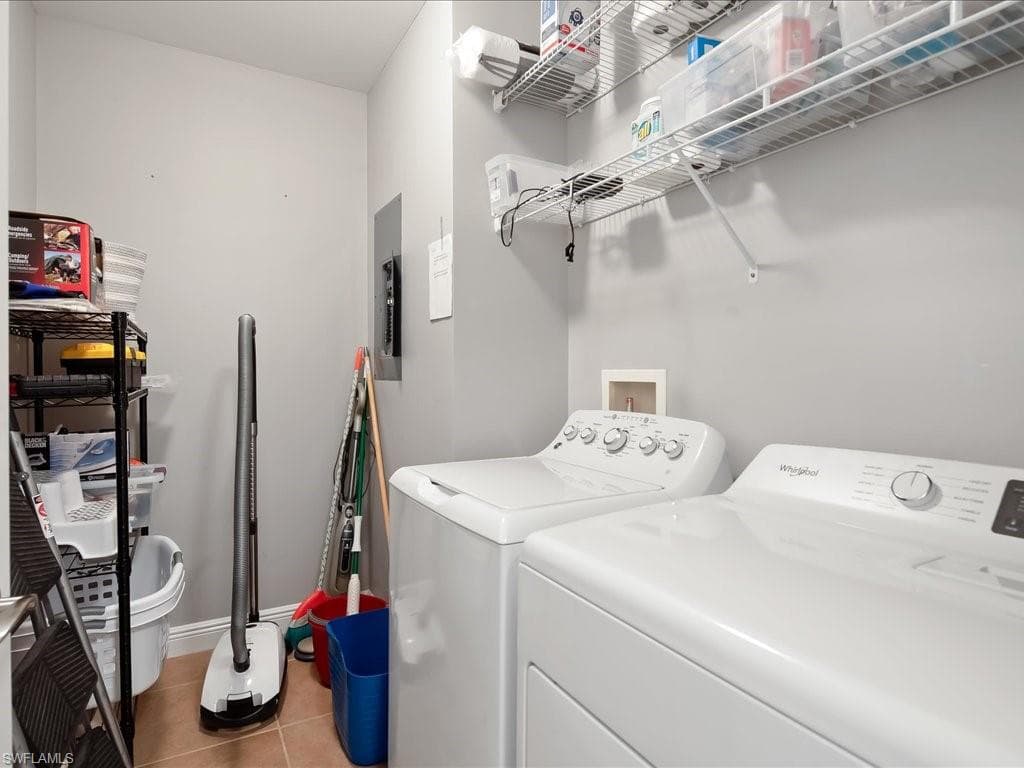 Laundry room featuring light tile patterned flooring, washing machine and clothes dryer, and electric panel