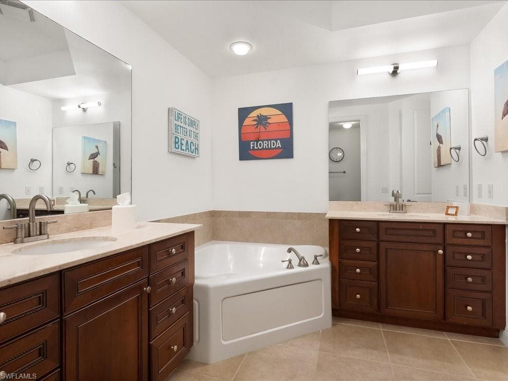 Bathroom with two vanities, a garden tub, and light tile patterned floors