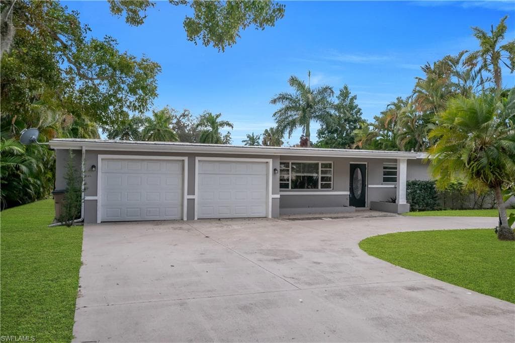 Single story home featuring a front lawn, stucco siding, driveway, and an attached garage